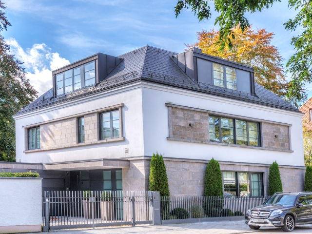 Moderne weiße Stadtvilla mit Naturstein-Fassadenelementen und Zufahrt – Symbolbild zu Immobilienpreisen in Bogenhausen