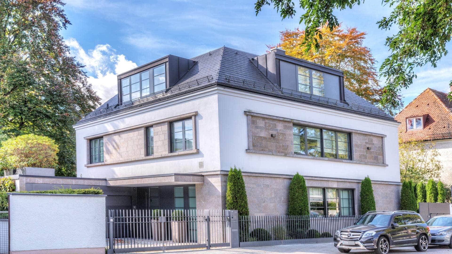Weiße Neubau-Villa mit Dachgauben und gepflasterter Einfahrt in München-Bogenhausen