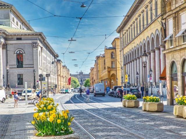 Historische Straßenzeile mit klassizistischen Gebäuden und Blumenkübeln im Münchner Lehel