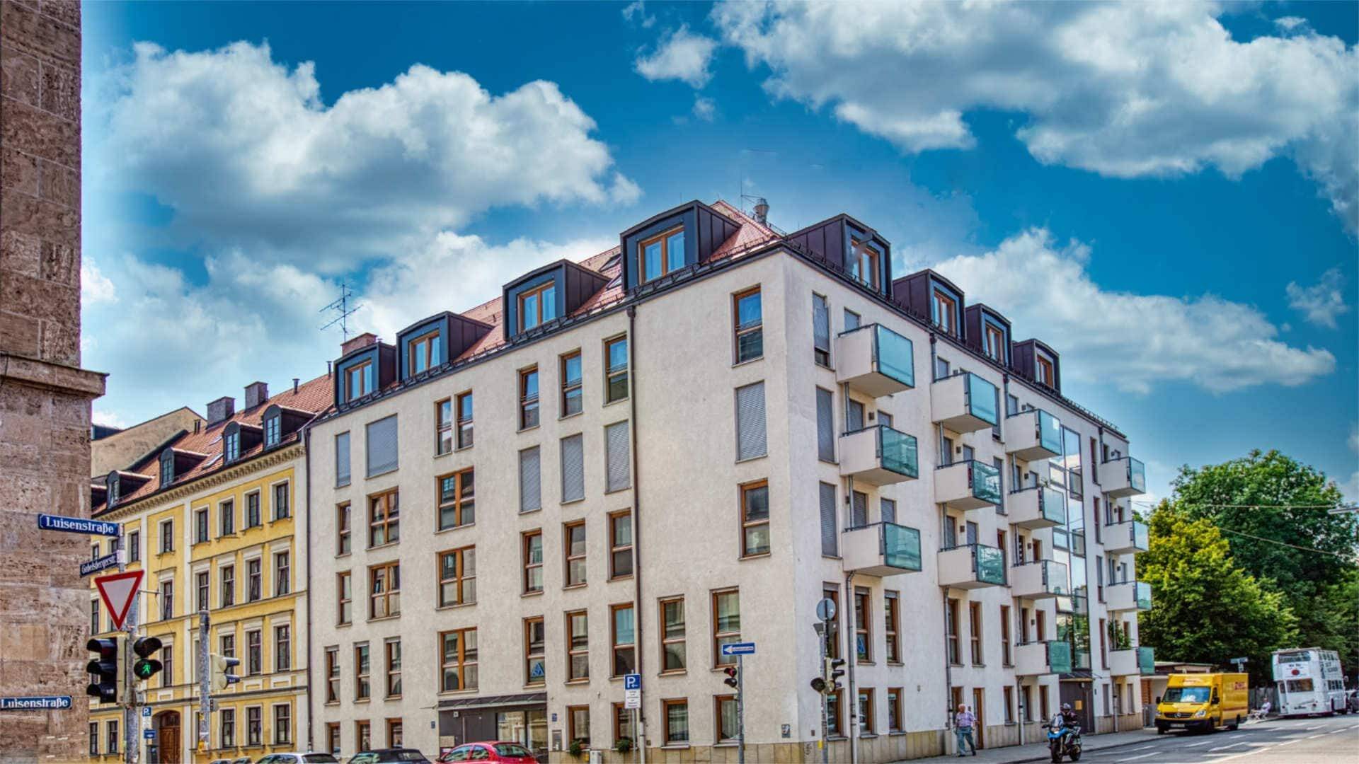 Cremefarbenes Altbau-Eckhaus mit Balkonen und Dachgauben in der Münchner Maxvorstadt