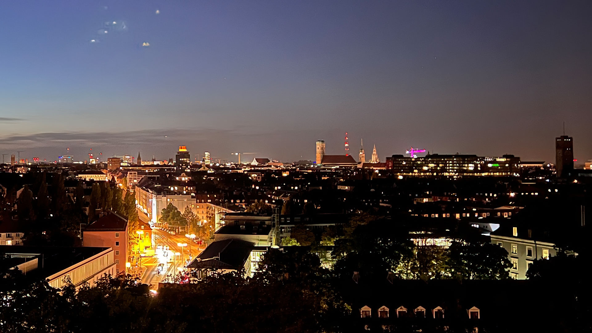 Beleuchtete Skyline von München bei Dämmerung mit Straßenverkehr