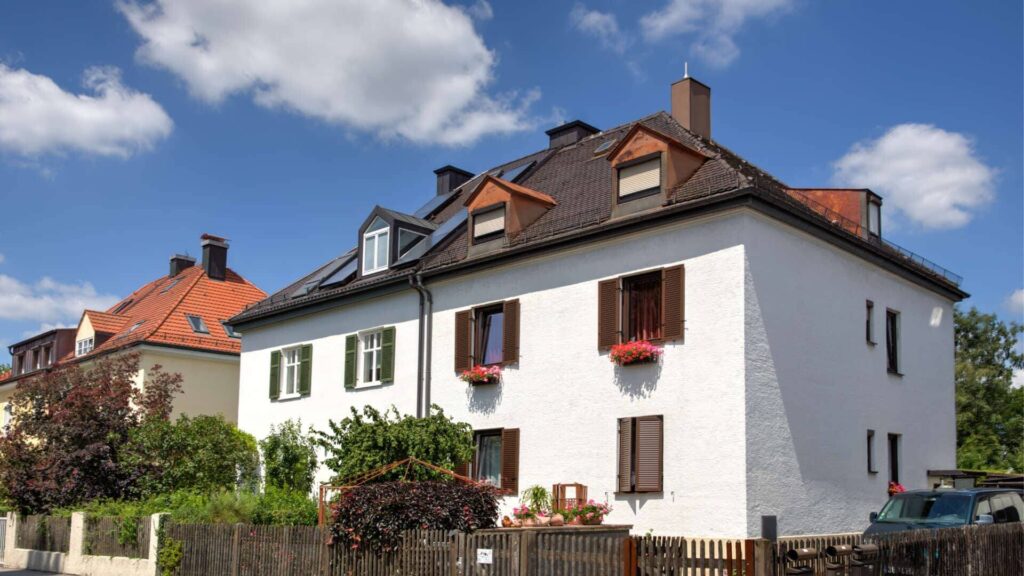 Weißes Wohnhaus mit roten Fensterläden und Gartenzaun