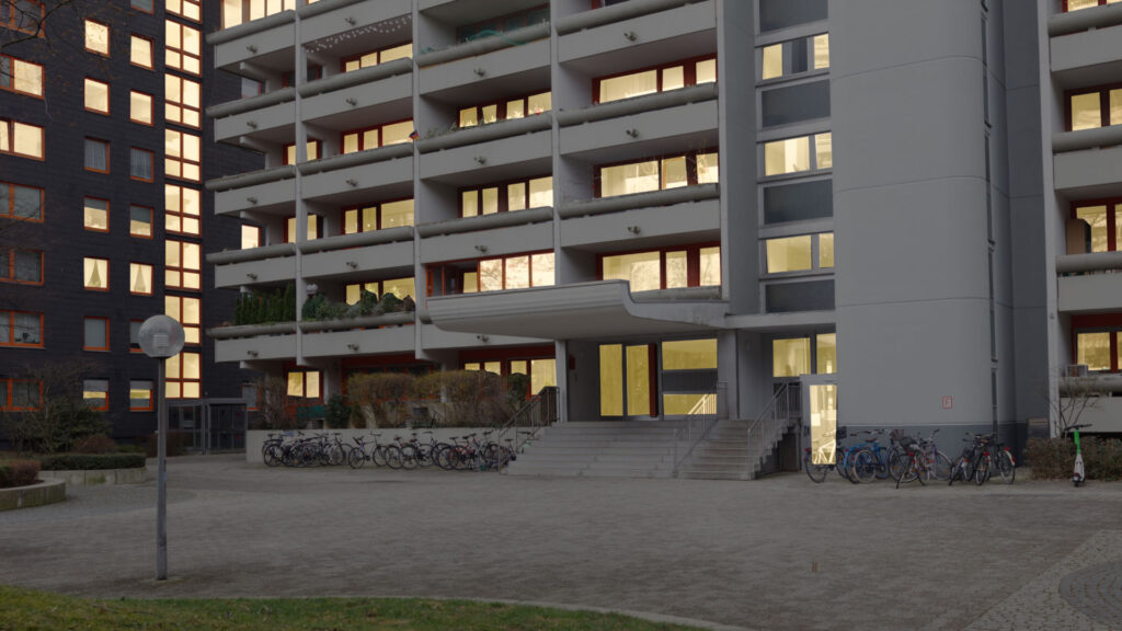 Illuminated facade of the Laimer apartment complex with balconies at dusk