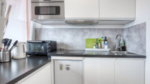Kompakte Einbauküche der Laimer Wohnung mit Arbeitsplatte, Mikrowelle und Spüle