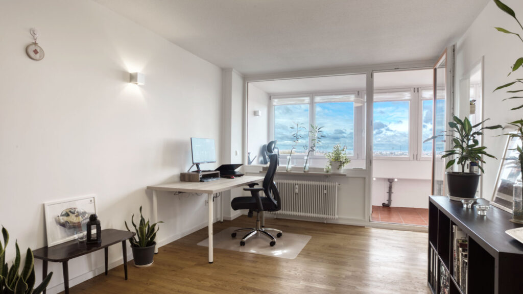 Furnished living space of the Laim apartment with desk, office chair, and sideboard