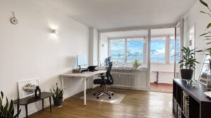 Furnished living space of the Laim apartment with desk, office chair, and sideboard