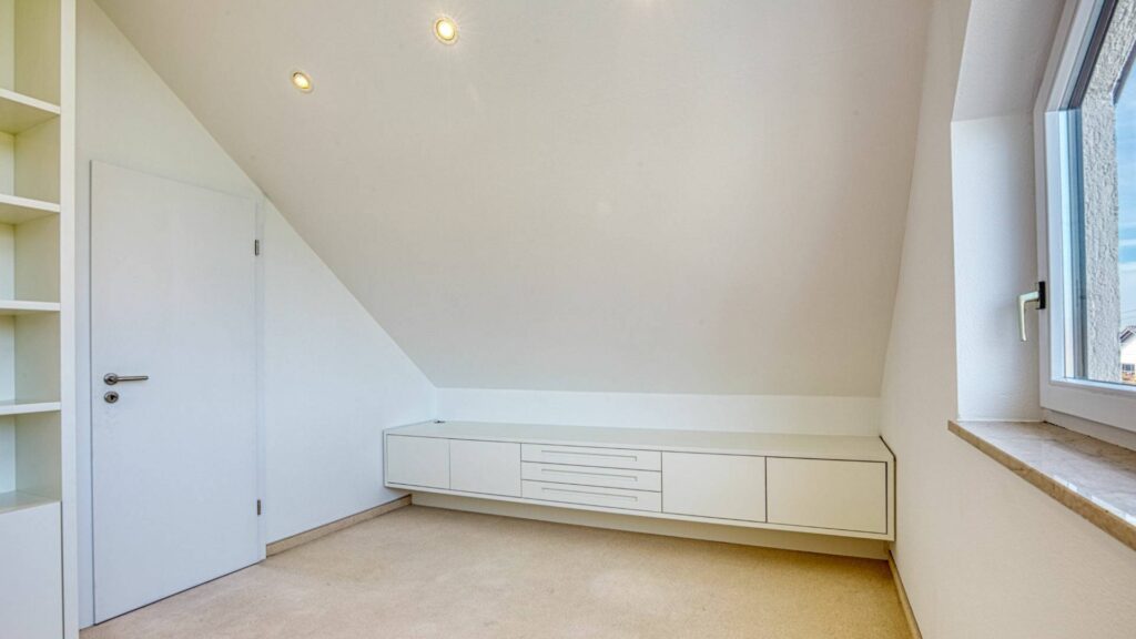 Leeres Dachgeschosszimmer des Lerchenauer Hauses mit eingebautem Sideboard unter der Dachschräge