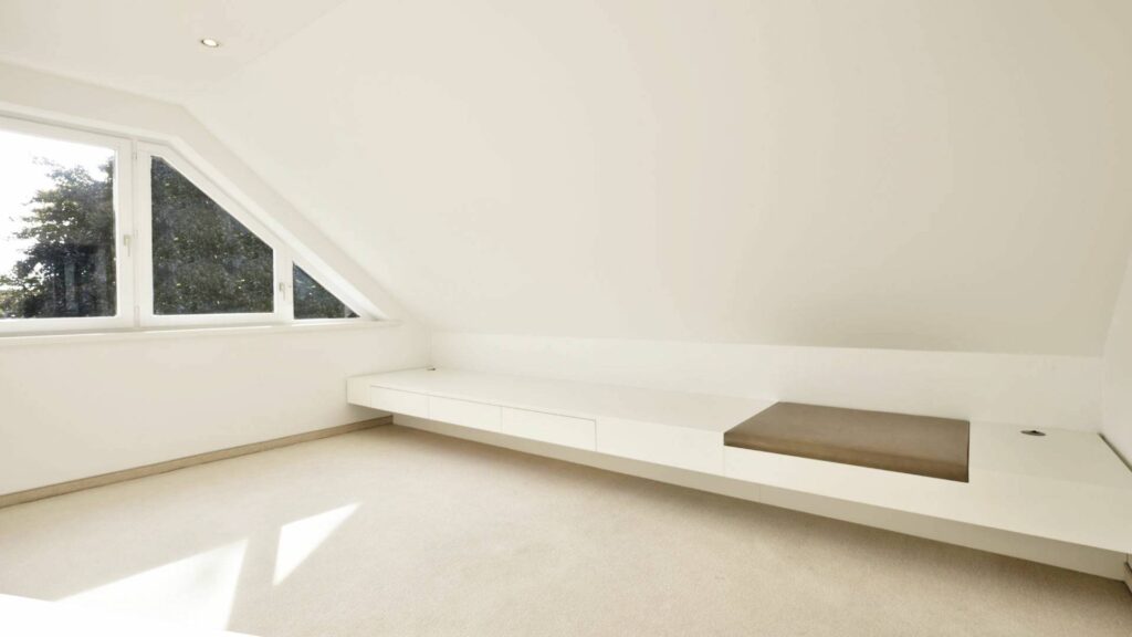 Leeres Dachgeschosszimmer des Lerchenauer Hauses mit Dachschräge und eingebauter Sitzbank