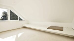Leeres Dachgeschosszimmer des Lerchenauer Hauses mit Dachschräge und eingebauter Sitzbank
