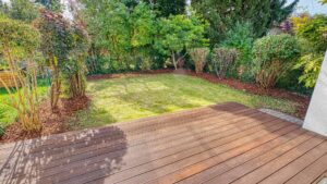 Holzterrasse des Lerchenauer Hauses mit Blick auf den grünen, dicht bepflanzten Garten