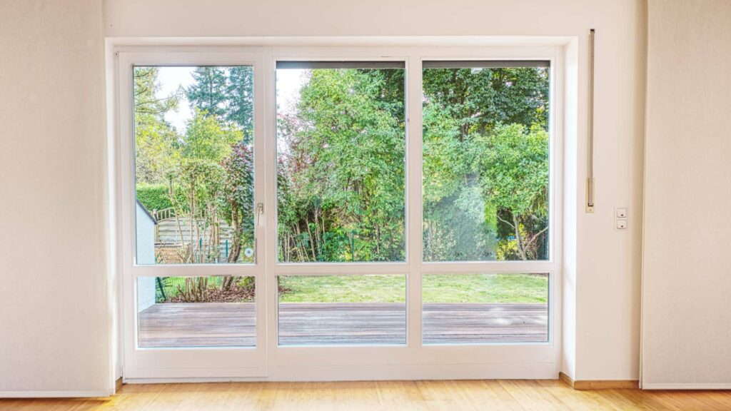 Leeres Wohnzimmer des Lerchenauer Hauses mit großer Terrassentür und Blick in den Garten