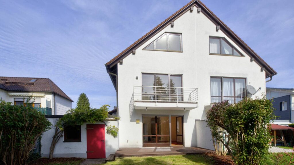 Weißes Einfamilienhaus in München-Lerchenau mit Satteldach, Balkon und rotem Eingangstor