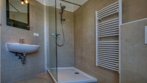 Kleines Badezimmer mit Glasdusche, Waschbecken und Heizkörper mit Handtuchhalter in einer Wohnung in der Maxvorstadt München