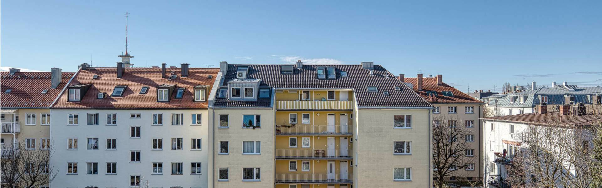 Blick über Dächer und Altbaufassaden benachbarter Häuser aus dem Fenster einer Dachgeschosswohnung in der Maxvorstadt München