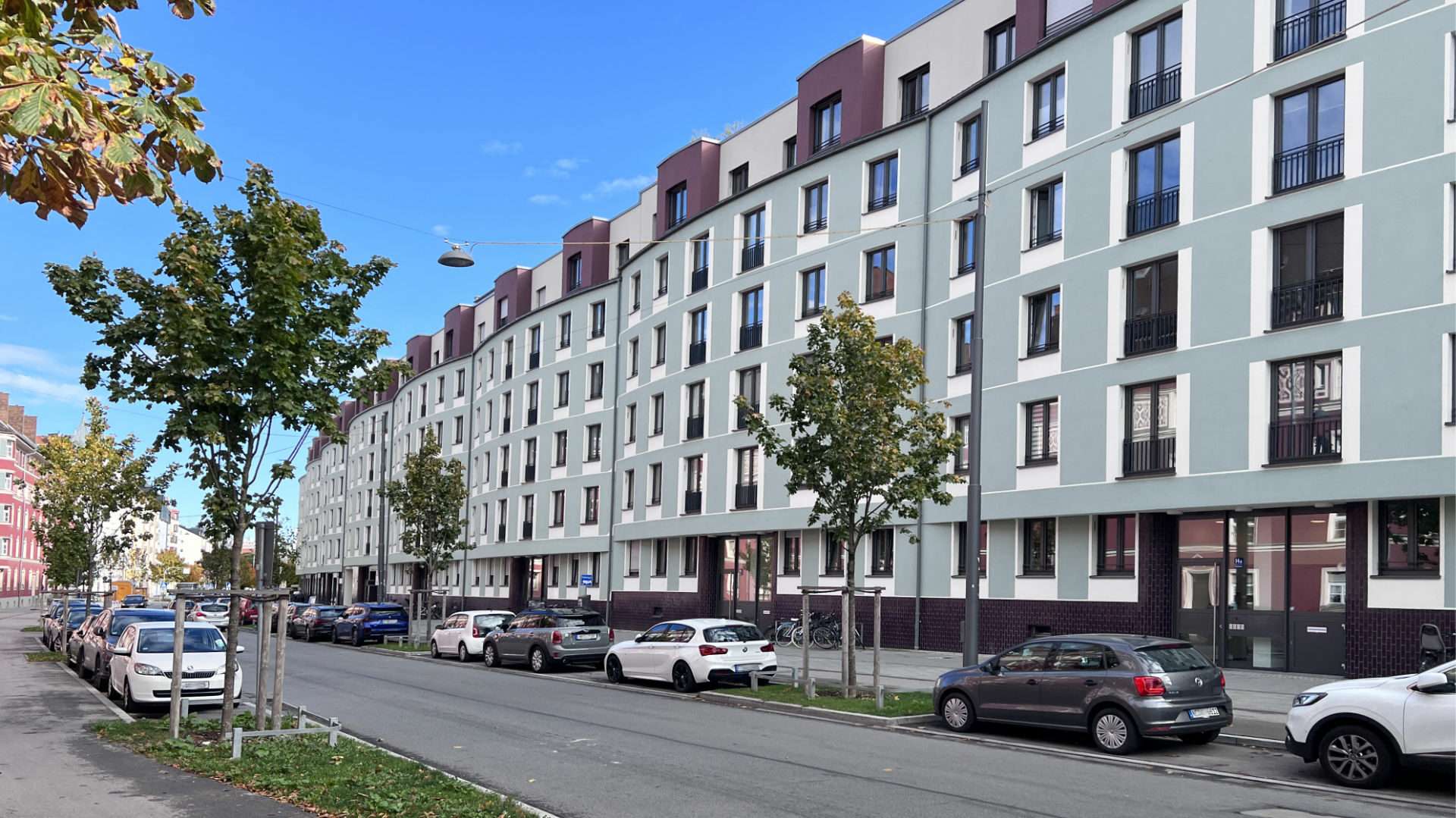 Straßenzeile mit modernen Mehrfamilienhäusern und parkenden Autos in München