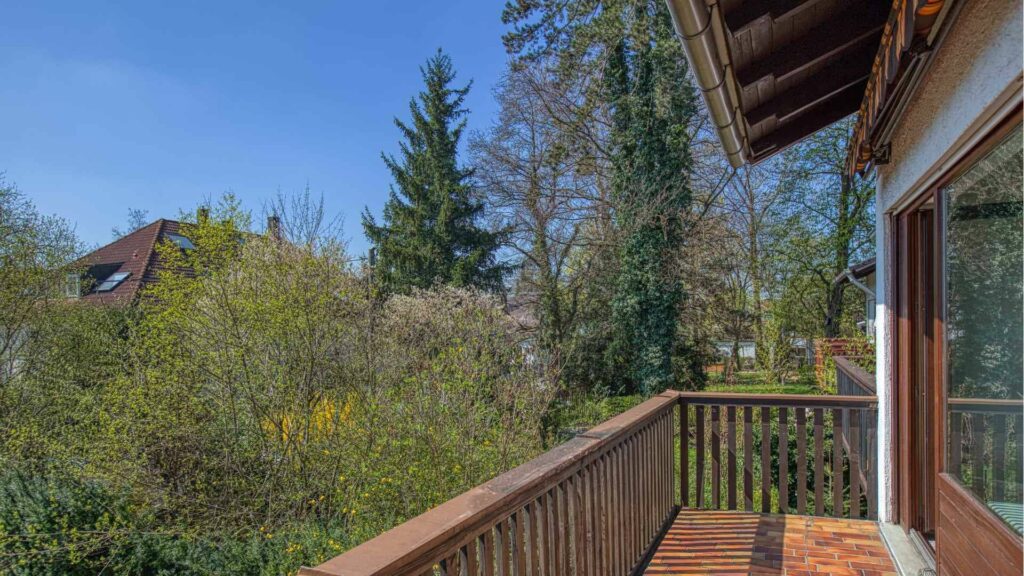 Holzbalkon mit Geländer und Blick auf Bäume und Nachbarhäuser beim Reihenhaus in Obermenzing.