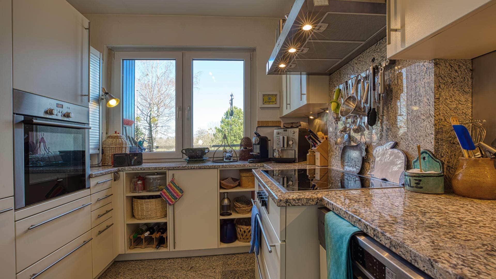 Existing kitchen area with granite worktop, windows and built-in cabinets in an apartment in Obermenzing