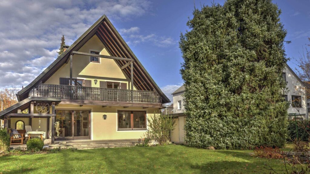 Rückansicht der Villa auf dem Grundstück in Obersendling mit Balkon und Rasenfläche
