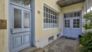 Entrance area with light blue doors and tiled front yard of a building on Orleansplatz in Munich