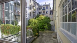 View through a window onto a green courtyard with old-style façades at Orleansplatz in Munich