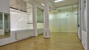 Unfurnished floor area with glass walls, columns and light wooden floors in a commercial unit on Orleansplatz