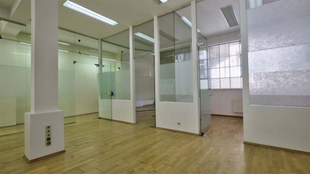 Empty commercial space with glass partitions, a pillar and wooden floors in a unit on Orleansplatz, Munich