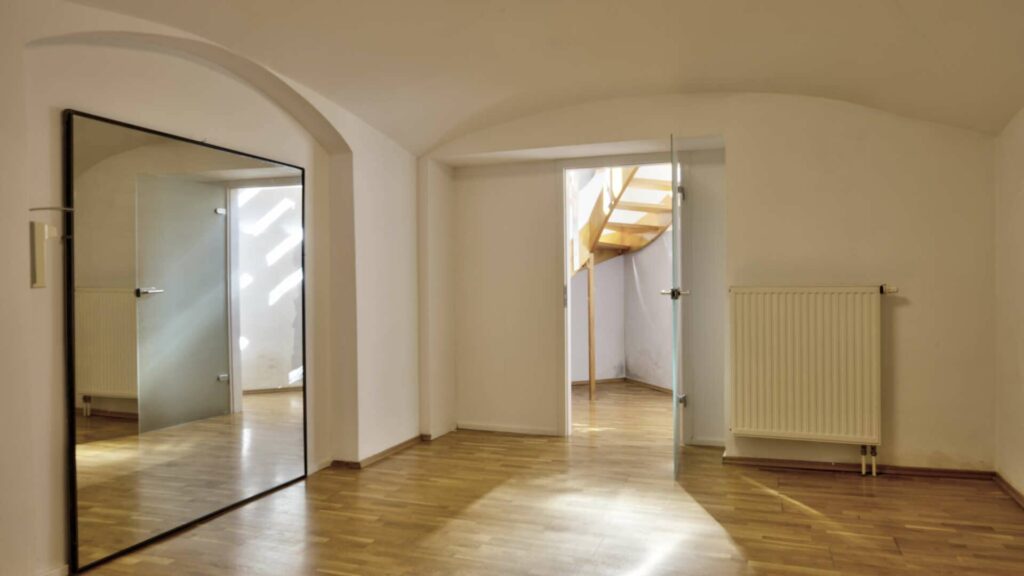 Bright room with a mirror, a vaulted ceiling, and views of a spiral staircase in an apartment on Orleansplatz