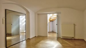 Bright room with a mirror, a vaulted ceiling, and views of a spiral staircase in an apartment on Orleansplatz