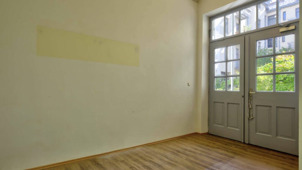Empty old building space with wooden floor and double doors to the courtyard in an apartment on Orleansplatz in Munich
