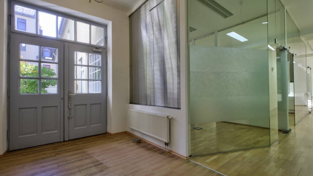 Empty space with double doors, milk glass wall and wooden floor in a commercial unit on Orleansplatz in Munich