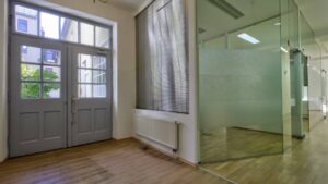 Empty space with double doors, milk glass wall and wooden floor in a commercial unit on Orleansplatz in Munich