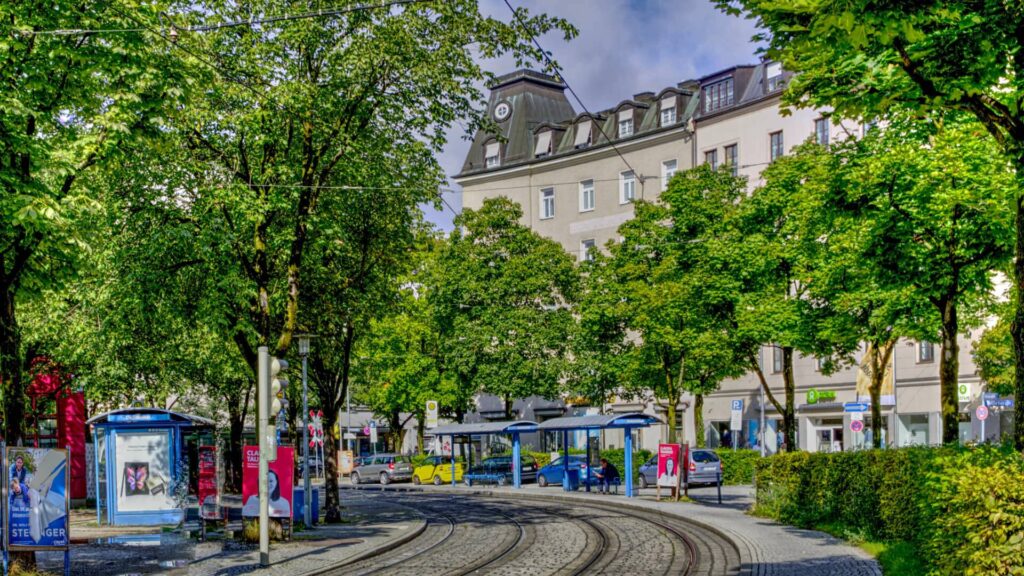 Street scene with a tram and trees in front of a building at Ostbahnhof in Munich