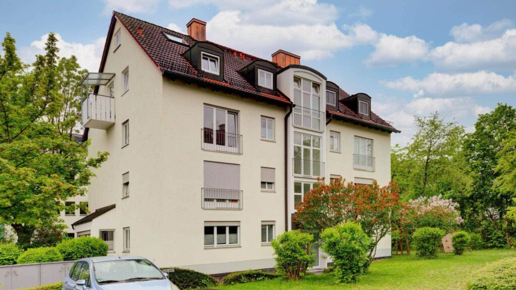 Multistory residential building with bay windows, a flat roof and a green front garden in Munich-Perlach.