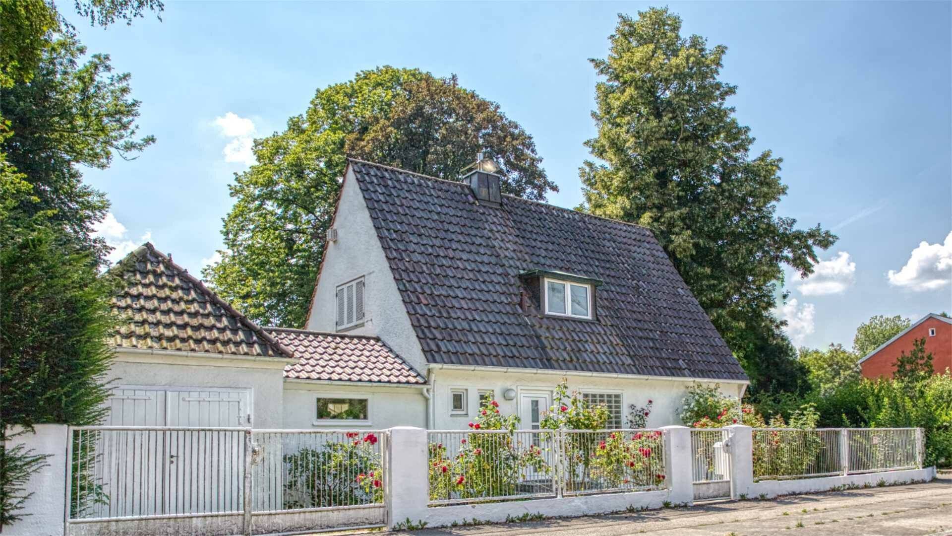 Weißes Wohnhaus mit steilem Satteldach und blühendem Vorgarten