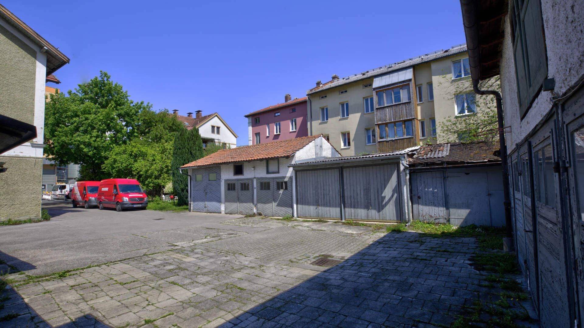 Gepflasterter Garagenhof mit mehreren Garagen und parkendem Fahrzeug auf einem Grundstück in Rosenheim.