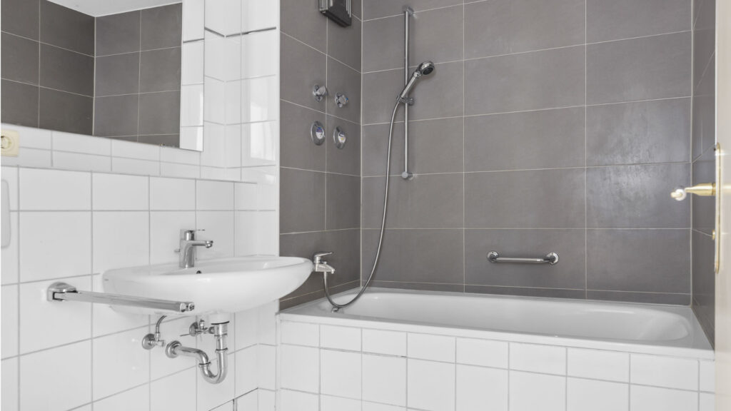 Tiled bathroom of the Schwabing apartment with a shower cubicle, bathtub, and vanity with a mirror