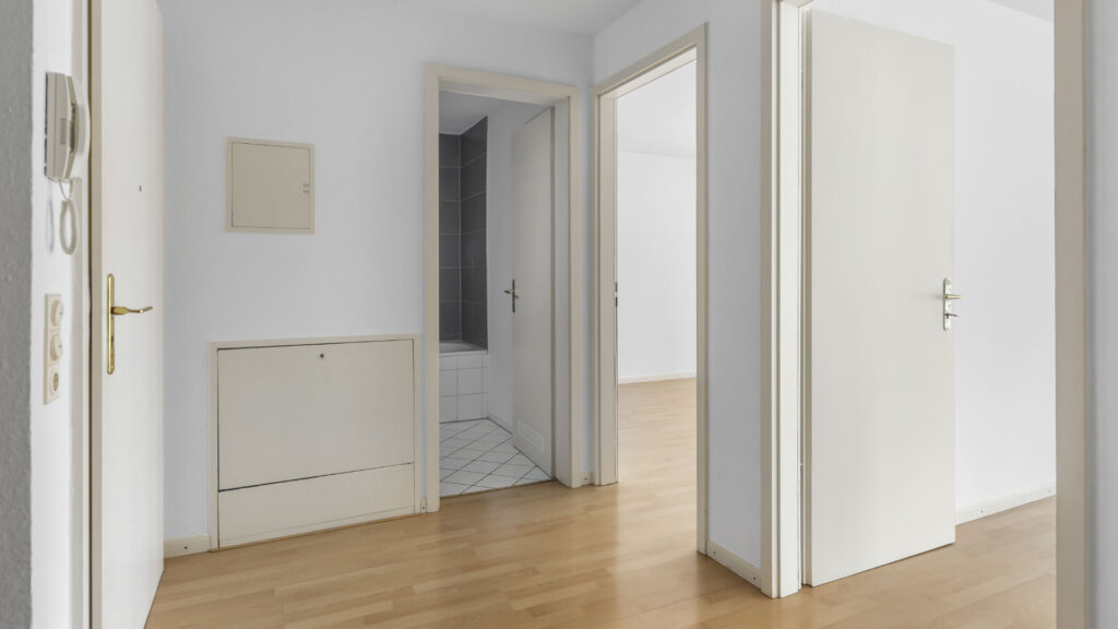 Hallway of the Schwabing apartment with parquet flooring and view into the bathroom and adjoining room