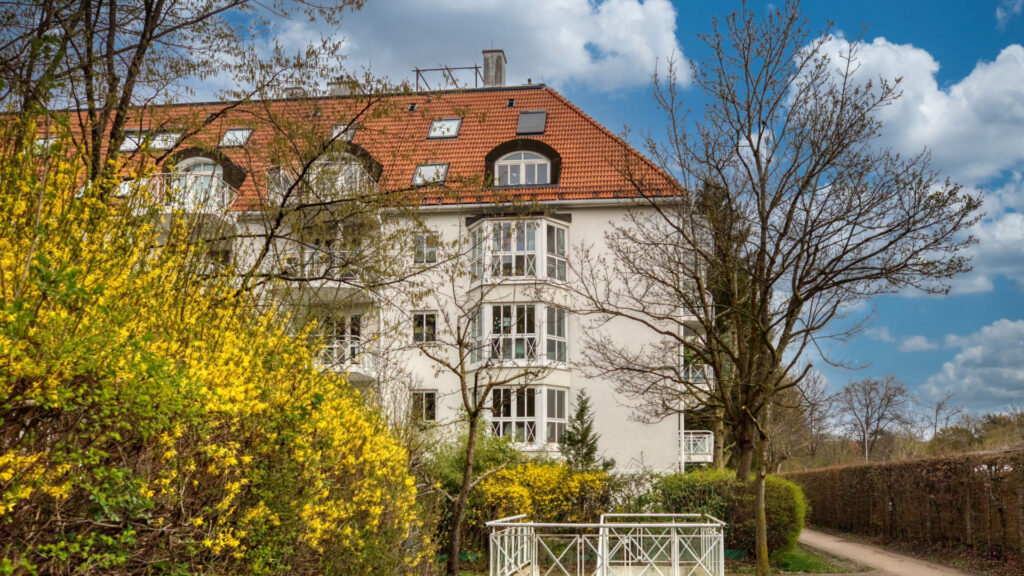 Exterior view of the old apartment building in Munich-Schwabing with bay windows and a blooming forsythia bush