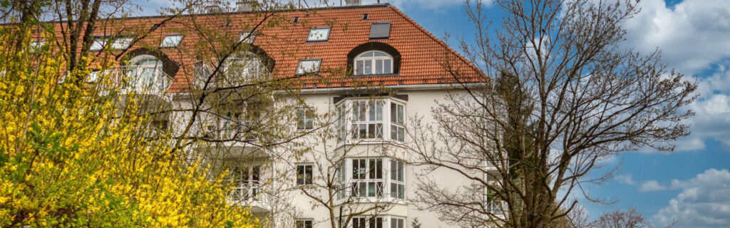 Narrow section of the historic building facade in Schwabing with blooming forsythia bush in the foreground