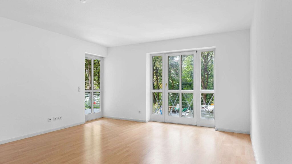 Empty bedroom of the Schwabing apartment with parquet flooring and large windows overlooking the garden