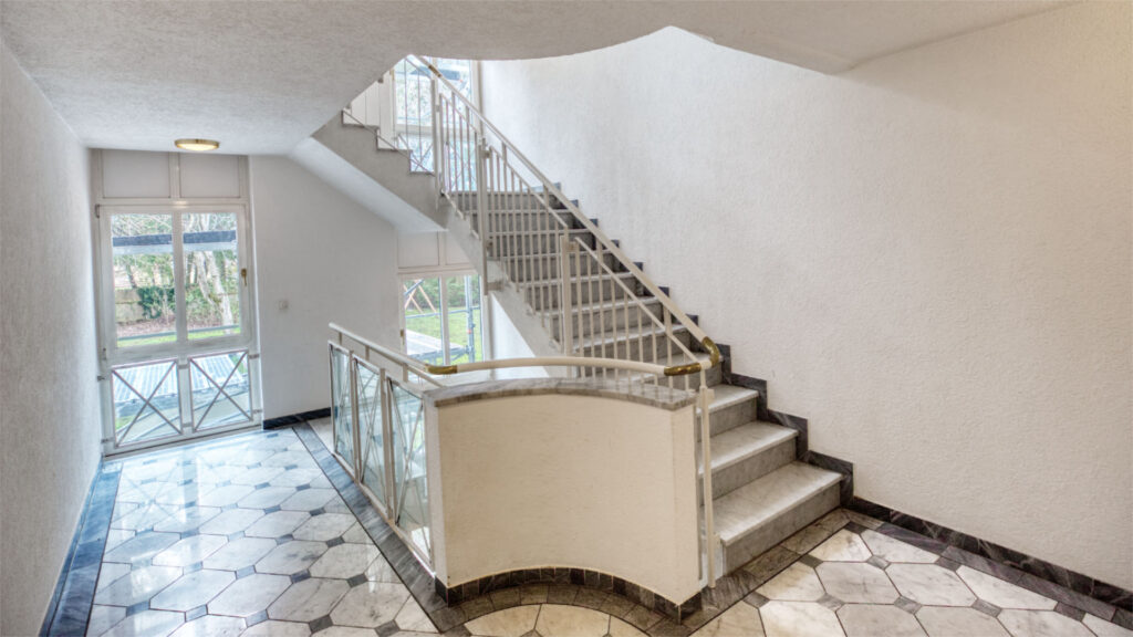 Well-maintained staircase of the Schwabing residential complex with tiled floor and curved staircase railing