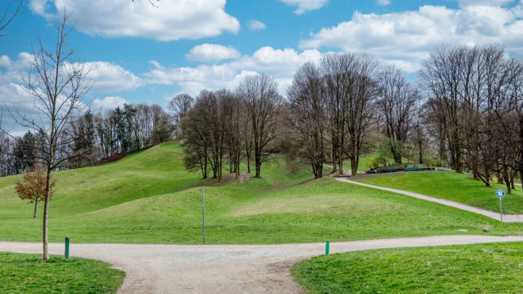 Paths and meadows of a park in Munich-Schwabing with bare trees in early spring