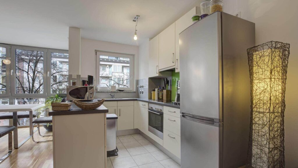 Offene Küche mit Kücheninsel und Edelstahlkühlschrank in einer Wohnung in München-Sendling