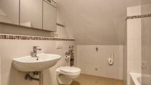 Badezimmer mit Dachschräge, Waschbecken, WC und Badewanne in einer Wohnung in München-Thalkirchen