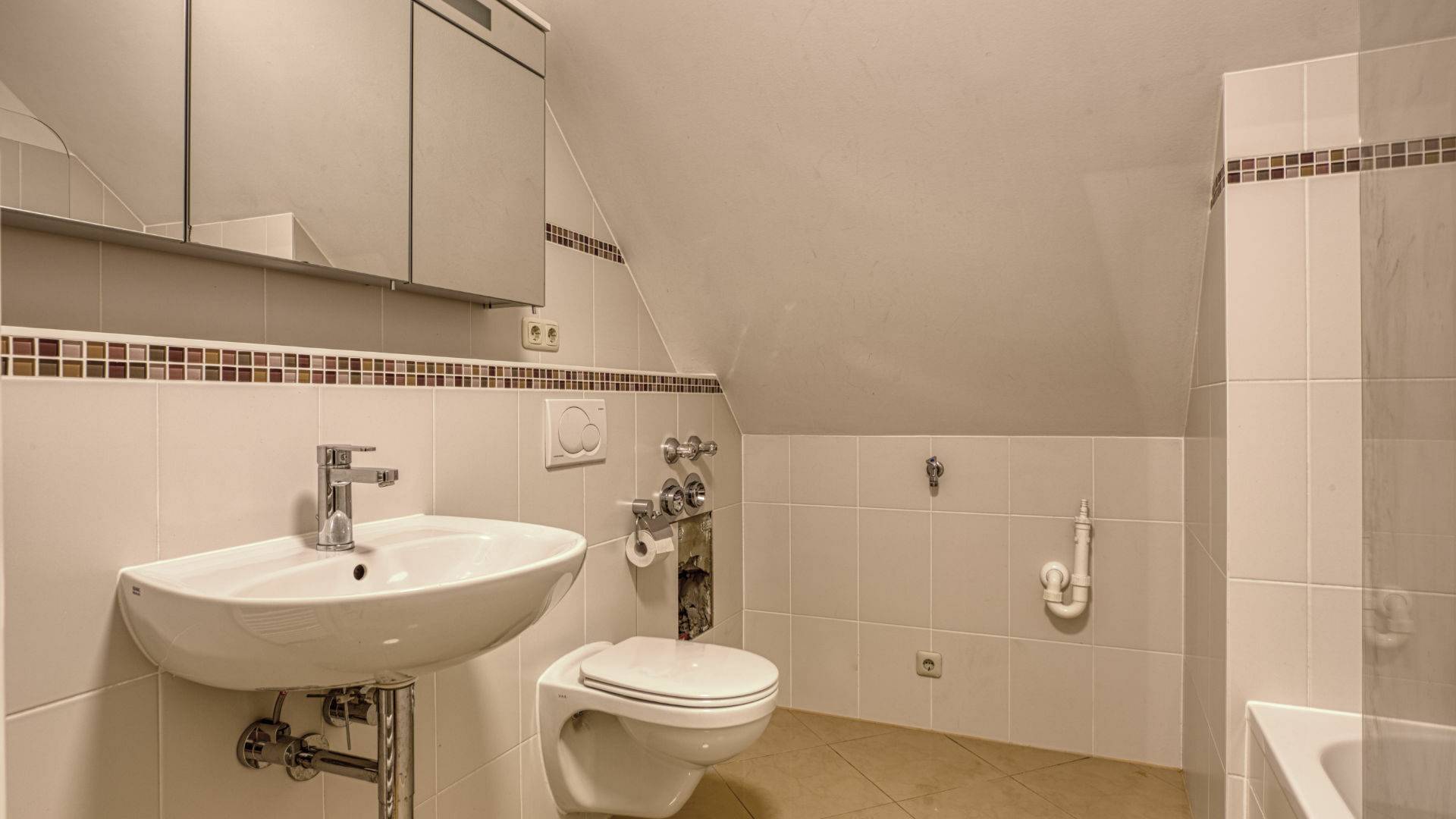 Badezimmer mit Dachschräge, Waschbecken, WC und Badewanne in einer Wohnung in München-Thalkirchen