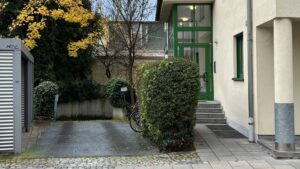 Gepflasterte Zufahrt mit Hecken und grüner Eingangstür zu einem Haus in München-Thalkirchen.