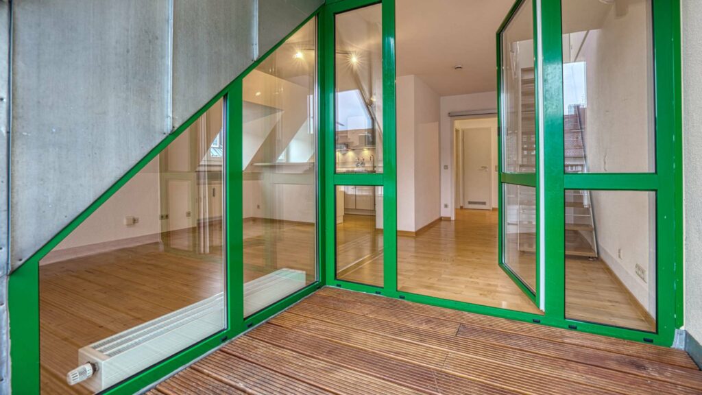 Green-framed window door leading to the roof terrace with a view of the living area of an apartment in Thalkirchen.