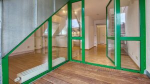 Grün gerahmte Fenstertür zur Dachterrasse mit Blick in den Wohnbereich einer Wohnung in Thalkirchen.