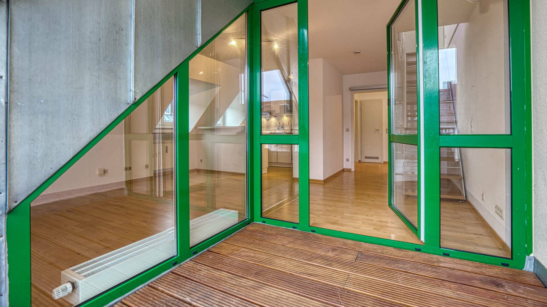 Grün gerahmte Fenstertür zur Dachterrasse mit Blick in den Wohnbereich einer Wohnung in Thalkirchen.