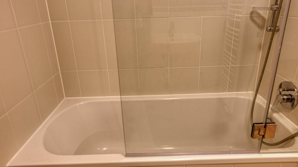 Close-up of a tiled bathtub with a glass partition and a shower in an apartment in Munich-Thalkirchen